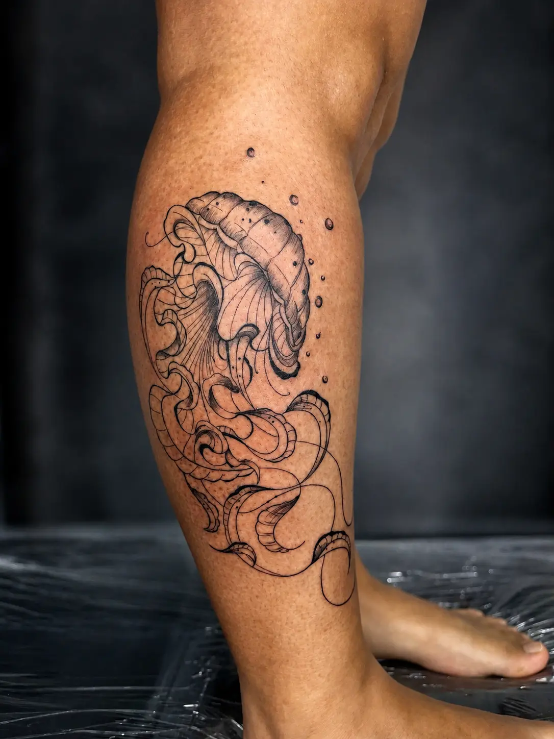 Tatuagem fineline de água-viva na panturrilha